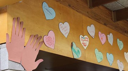 On the wall above the wood doorway there is a paper hand and six paper hearts.