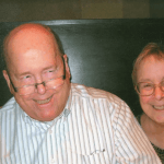 Ian M. Finlayson, a balding older man with glasses near the end of the bridge of his nose; wearing a pin-striped shirt; and Kathleen VanPaaschen, on older woman with gold-brown hair; wearing glasses at the top of her nose. Both people are against a grey background.