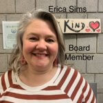 Erica Sims Board Member, woman with salt and pepper hair wearing a white and red striped shirt