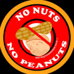 Graphic picture: With an orange outside circular rim; No Nuts No Peanuts in white lettering against a red background; graphic peanut and walnut with a line through both.