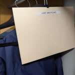 A beige file folder labeled "LOST AND FOUND" hanging in a closet on a metal hanger.