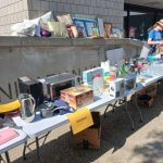 Courtyard sale tables displaying various household items and kitchen appliances.