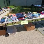 Table with folded children's clothing and a "CHILDREN'S CLOTHING" sign.